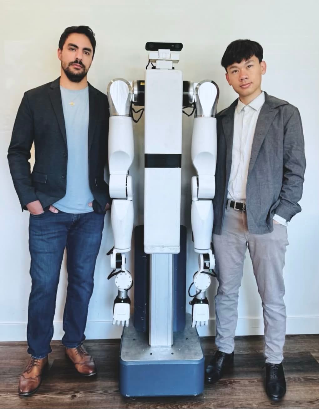 Feather's two co-founders standing either side of a Feather robot